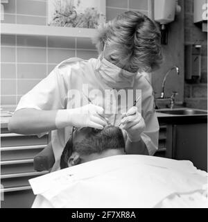 Un dentista della malattia centrale (CZB) nella caserma marina Willemsoord (MKWD) in Den Helder esamina i denti di un paziente (luglio 1989). Foto Stock