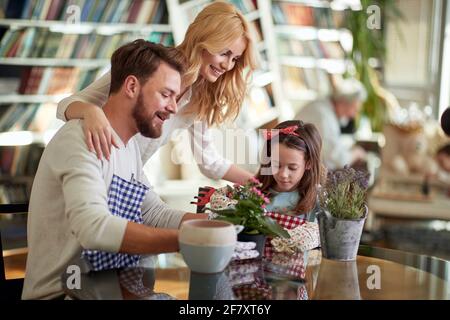 Felici genitori caucasici che piantano insieme alla loro figlia a casa Foto Stock