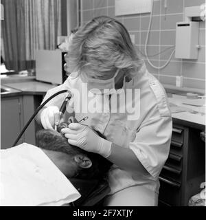 Un dentista della malattia centrale (CZB) nella caserma marina Willemsoord (MKWD) in Den Helder esamina i denti di un paziente (luglio 1989). Foto Stock