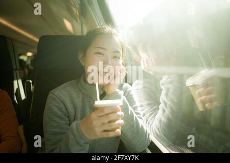 Ritratto di stile di vita di giovane felice e bella donna cinese asiatica viaggio in treno guardando attraverso la finestra bere caffè Foto Stock