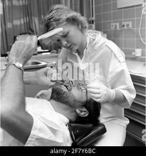 Un dentista della malattia centrale (CZB) nella caserma marina Willemsoord (MKWD) in Den Helder esamina i denti di un paziente (luglio 1989). Foto Stock