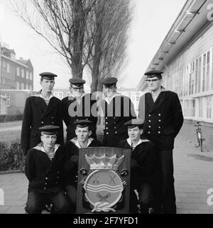Foto di classe realizzata sul sito delle caserme marine di Amsterdam (MKAD) presso i corsi tecnici della Royal Netherlands Marine (Toka). Una classe con pale di vari gruppi di servizio si pone con lo stemma del Tockm. Foto Stock