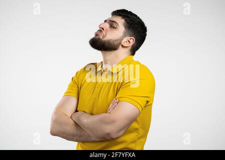 Uomo arrabbiato offeso che tiene le braccia incrociate e fissando la macchina fotografica con lo sguardo scettico e diffidente, ritenendosi pazzo a qualcuno. Espressioni facciali umane Foto Stock