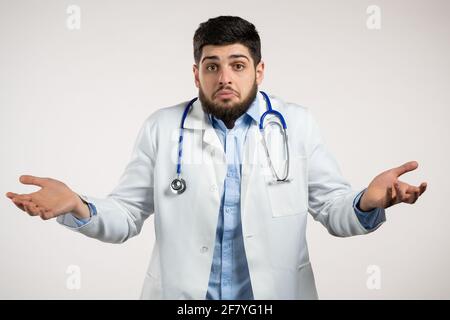 L'uomo medico incerto in cappotto medico gli avvolge le braccia, fa gesto di non so, attenzione, non può aiutare nulla .Doc su sfondo bianco Foto Stock