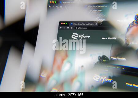 Milano, Italia - 10 APRILE 2021- il logo della società pfizer sullo schermo del laptop visto attraverso un prisma ottico, interpretazione creativa. Immagine dinamica e unica f Foto Stock