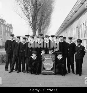 Foto di classe realizzata sul sito delle caserme marine di Amsterdam (MKAD) presso i corsi tecnici della Royal Netherlands Marine (Toka). Una classe con piloti della 3° classe (Mach 3) si pone con lo stemma del Tkm e il loro supervisore, un sergente-machinista (SGTMACH). Foto Stock