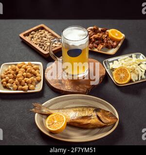 Tazza di birra con pesce alla griglia, piselli, spuntini al formaggio Foto Stock