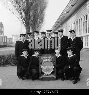 Foto di classe realizzata sul sito delle caserme marine di Amsterdam (MKAD) presso i corsi tecnici della Royal Netherlands Marine (Toka). Una classe con elettricisti della prima classe (Elmnt 1) si pone con lo stemma del Tkm. Foto Stock