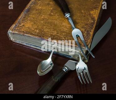 Un libro di cucina molto vecchio e utensili classici. Tasto basso. Foto Stock