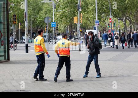 Gli uomini di ambulanza provano ad aiutare un uomo mentalmente instabile che sta mentendo nella strada comportandosi molto stranamente. Foto Stock