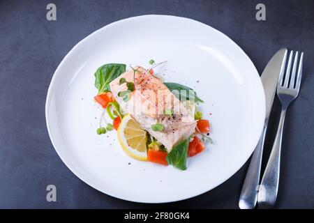 Trota (salmone) con verdure, limone e micrograni, cotti con il metodo confit. Piatto francese tradizionale. Passo dopo passo. Primo piano. Foto Stock