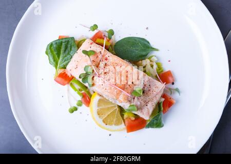 Trota (salmone) con verdure, limone e micrograni, cotti con il metodo confit. Piatto francese tradizionale. Passo dopo passo. Vista dall'alto. Foto Stock