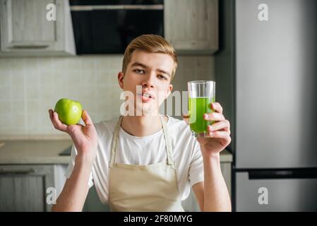 Giovane uomo forte che ha leggero breakfast.Apple succo in cucina. Frutta fresca e cibo sano Foto Stock