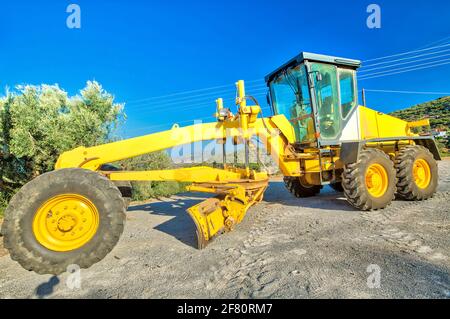 Grandangolo di bulldozer giallo su ruote per la posa di calcestruzzo asfaltato. Lavori di costruzione su strada. Lavoro in corso, macchina industriale. Foto Stock