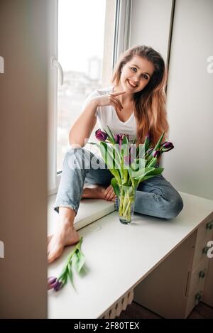 Amabile ragazza femminile nel fine settimana mattina. Bouquet di tulipani Foto Stock