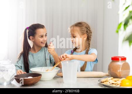 Due bambine preparano biscotti di Natale in cucina Foto Stock