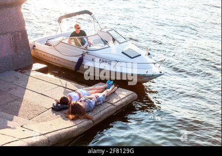 San Pietroburgo, Russia - 27 agosto 2016: Due ragazze stanno riposando su un argine di granito accanto ad un motoscafo ormeggiato Foto Stock