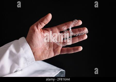 Mano del medico che tiene un allineatore dentale libero Foto Stock