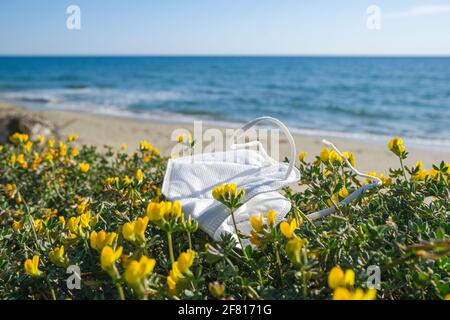 Maschera facciale protettiva monouso scartata sull'habitat delle piante marine, medico covid19 inquinamento marino pandemico Foto Stock