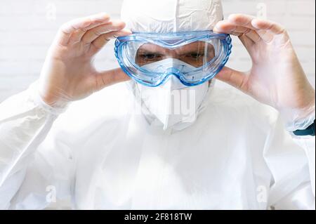 Infermiere di sesso maschile che indossa tuta protettiva e abiti da lavoro, indossando occhiali protettivi e maschera Foto Stock