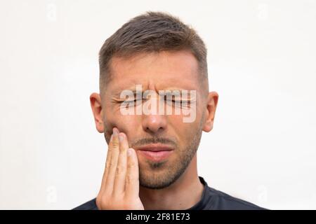 L'uomo sente forte dolore ai denti. Uomo che soffre di mal di denti, malattie dentali o malattie orali. Problema ai denti Foto Stock