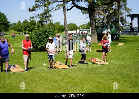 I maschi e le femmine giocano un gioco di lancio di sacco di fagioli all'evento del fine settimana di Walleye al parco del lago, come una comunità si riuniscono. Foto Stock