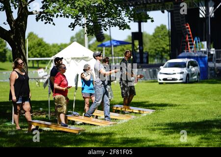 I maschi e le femmine giocano un gioco di lancio di sacco di fagioli all'evento del fine settimana di Walleye al parco del lago, come una comunità si riuniscono. Foto Stock