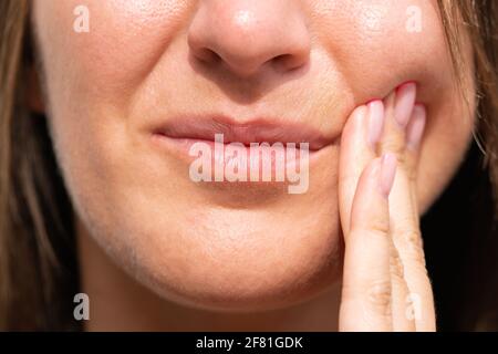 Closeup di donna viso sensazione di dolore ai denti. Donna che soffre di mal di denti, malattie dentali o malattie orali Foto Stock