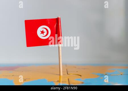 Una piccola bandiera della Tunisia ruotata su un bastone di legno fissato sul globo Foto Stock