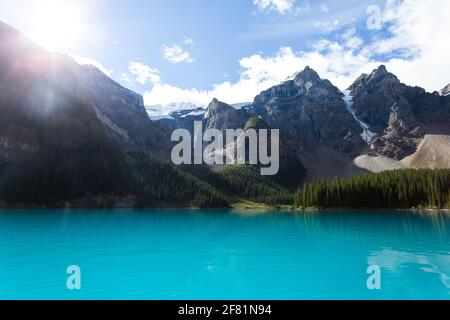 il sole si sveglia dietro una vista di montagna da un turchese luminoso lago Foto Stock