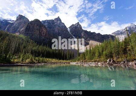 Vista su alcune alte montagne dietro un lago verde turchese in una giornata di sole Foto Stock