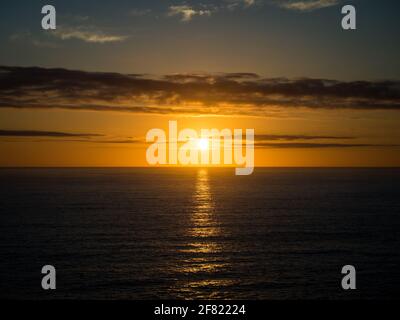 Un bel tramonto dorato sull'orizzonte dell'oceano in una calda serata estiva. Foto Stock