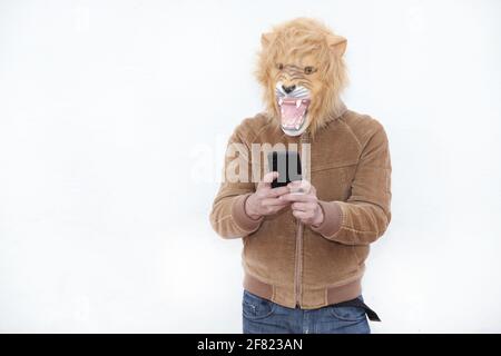 Un uomo con un leone ruggito maschera piena usando il suo telefono isolato su sfondo bianco Foto Stock