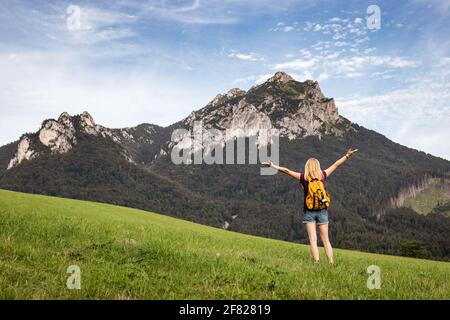 Donna felice che ama fare escursioni in montagna. Concetto di viaggio e stile di vita attivo. La spensierata turista femminile si sente aria fresca nella natura Foto Stock