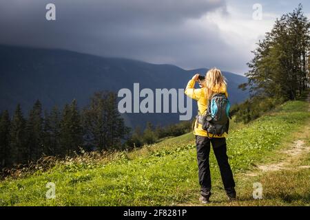 La tempesta sta arrivando. Maltempo in montagna. Donna che fotografa sul telefono cellulare durante l'escursione in montagna Foto Stock