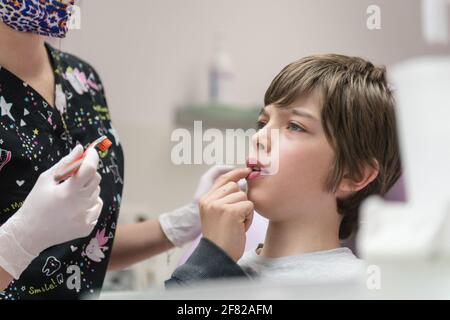 Dentista che dimostra al ragazzo come spazzolare i denti in un dentale clinica Foto Stock