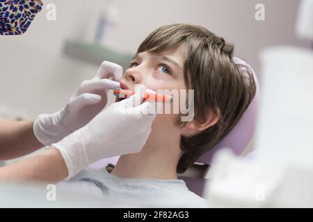 Dentista che dimostra al ragazzo come spazzolare i denti in un dentale clinica Foto Stock