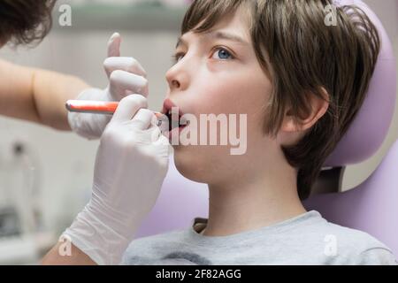 Dentista che dimostra al ragazzo come spazzolare i denti in un dentale clinica Foto Stock