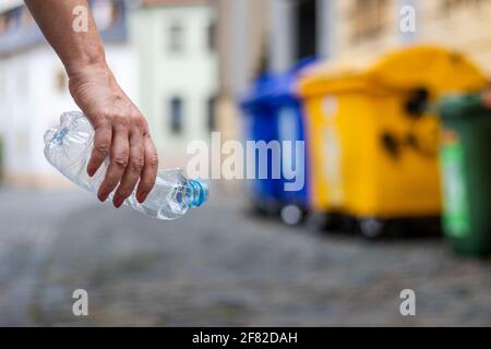 Problemi ambientali. Bottiglia di plastica con mano in strada. Riciclaggio dei rifiuti di plastica Foto Stock