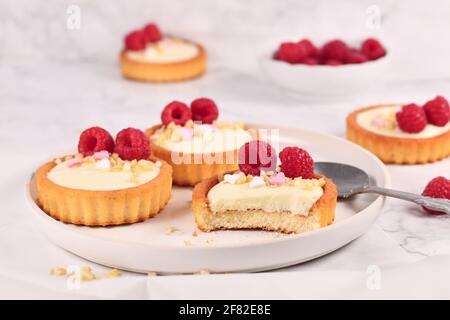 Piccola pasticceria a base di tartine con panna bianca, ricoperta di lamponi e mandorle Foto Stock