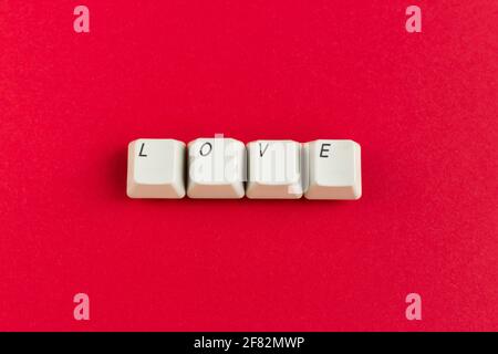 Tasti della tastiera del computer con la parola d'amore scritta utilizzando i tasti bianchi su sfondo rosso. Carta di San Valentino. Concetto di vacanza. Foto Stock