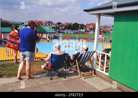 I vacanzieri presso il loro chalet sulla spiaggia vicino alla piscina con spruzzi del Queen's Park. Mablethorpe. Lincolnshire. Inghilterra, Regno Unito Foto Stock