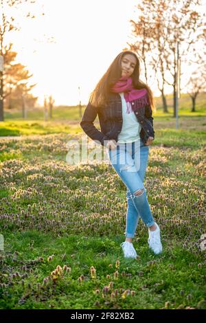 Ritratto all'aperto di una ragazza adolescente mista in un boschetto di ciliegi al tramonto in primavera. Foto Stock