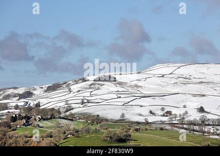 Middleton-in-Teesdale, Teesdale, County Durham, Regno Unito. 11 aprile 2021. Regno Unito Meteo. Gli acquazzoni di neve sopra Middleton-in-Teesdale lasciano una linea di demarcazione stellare fra l'inverno nelle colline e le condizioni primaverili nella valle. Credit: David Forster/Alamy Live News Foto Stock