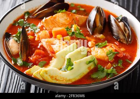 Zuppa ricca di frutti di mare, verdure e avocado da vicino in una ciotola sul tavolo. Orizzontale Foto Stock