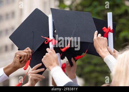 Cappelli di laurea e diplomi in mani studentesche, primo piano Foto Stock