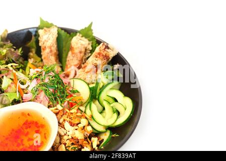 Piatto vietnamita di pasta fredda di riso-vermicelli condita con erbe fresche, insalata fresca e involtini primaverili Foto Stock