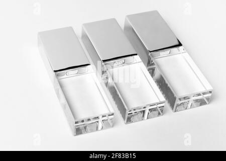 Tre unità USB trasparenti in vetro con coperchio in metallo su sfondo grigio. Layout. Primo piano. Spazio di copia. Un'alta risoluzione. Foto Stock