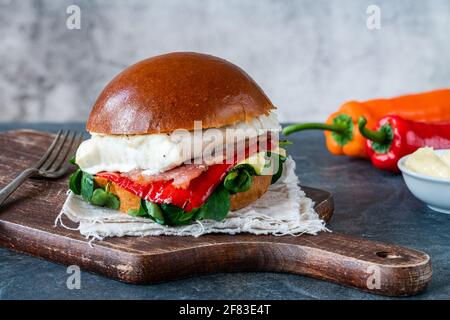 Sandwich di halibut alla griglia in brioche con pancetta, pepe rosso romano, zucchine e lattuga di agnello Foto Stock