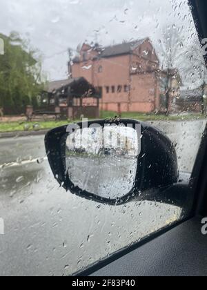Un'immagine verticale del finestrino di un'auto coperto di pioggia goccioline Foto Stock